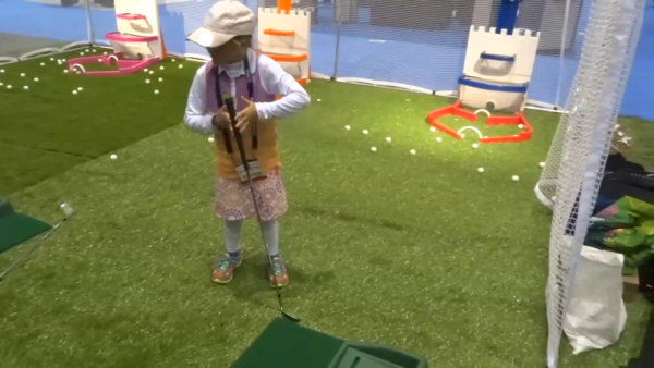 Child playing mini golf indoors