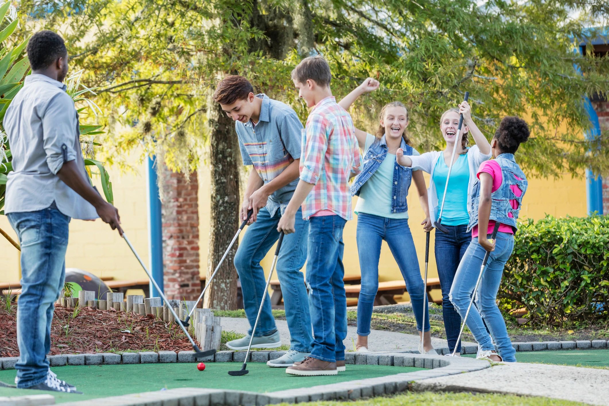 Teens playing miniature golf together